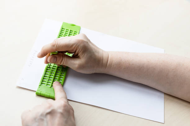 hand prints words in braille with slate and stylus