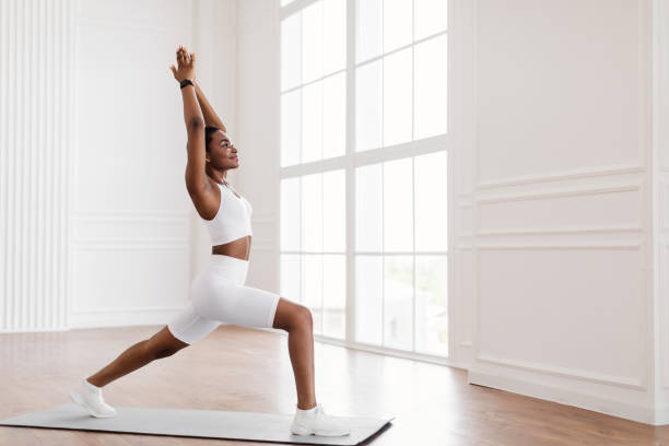 istock Young black woman doing forward lunges on mat 1328898259