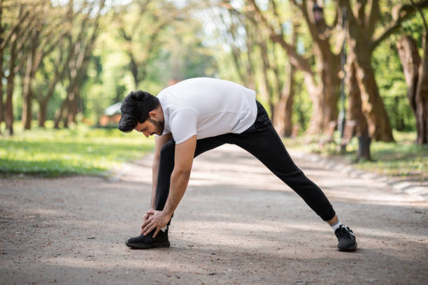 istock Healthy muslim guy stretching body before run at park 1328898456