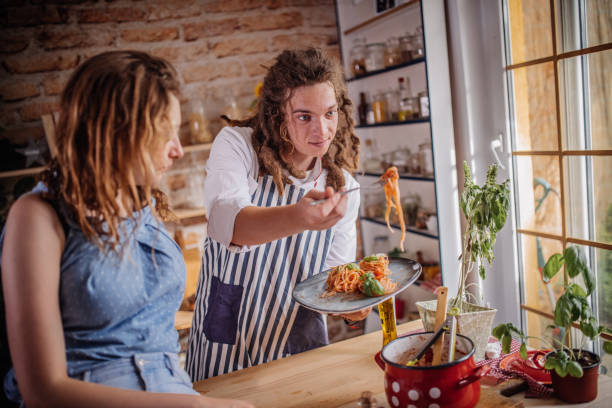 istock Playful young couple having dinner together. Eating spaghetti 1328900202