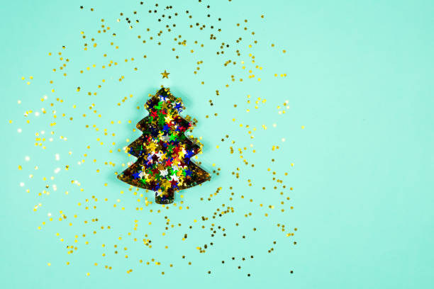 istock Christmas tree baking mold with colorful sparkles inside on a light blue background. Flat lay. View from above. Place for an inscription. Base for a postcard. 1328900486