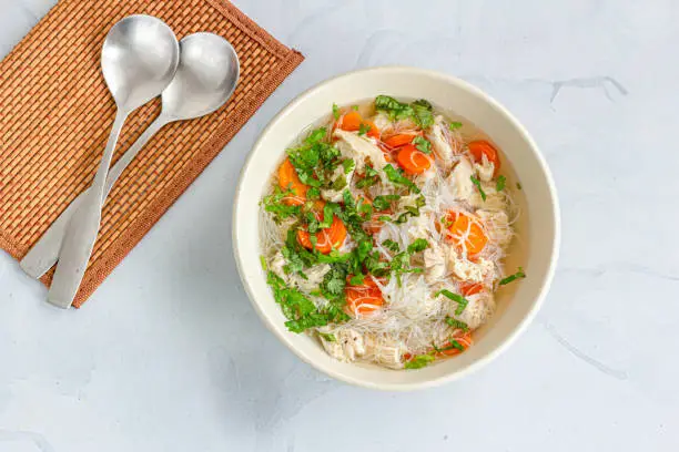 A Bowl of Healthy Chicken Noodle in a Bowl With a Spoon Top Down Photo