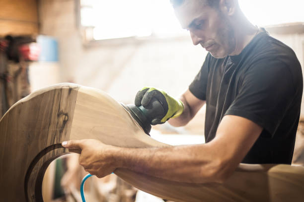 Craftsman using electric sander, to smoothen the wood texture Craftsman is using an electric sander, to smoothen the wood texture. Carpentry concept with wood worker with grinding machine power tool in factory stock pictures, royalty-free photos & images