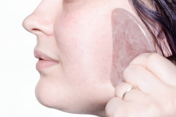 istock woman massages cheek with quartz scraper close up 1328901636