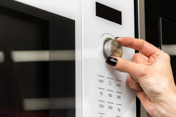 istock Female pushes button on microwave oven close up 1328903698