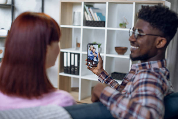 istock Multicultural couple using mobile for video call with family 1328904958