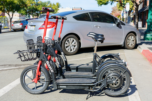 Three Razor Share electric rideshare seated e-scooters with front basket parked on the street. Side view. - San Diego, California, USA - 2021