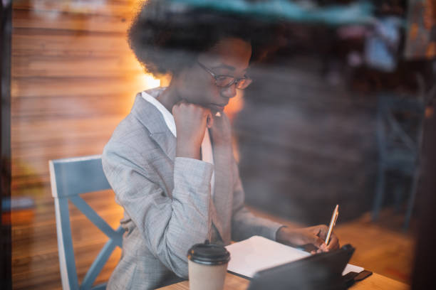 istock African woman taking notes and using tablet at cafe 1328909167