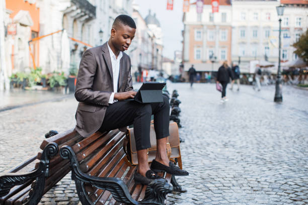 istock Focused black man sitting on bench and working on tablet 1328911197