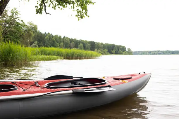 Boat , canoe-kayak on water , lake on background of green summer forest. Concept of sport leisure activities, recreation, entertainment in nature. Copy space for text.