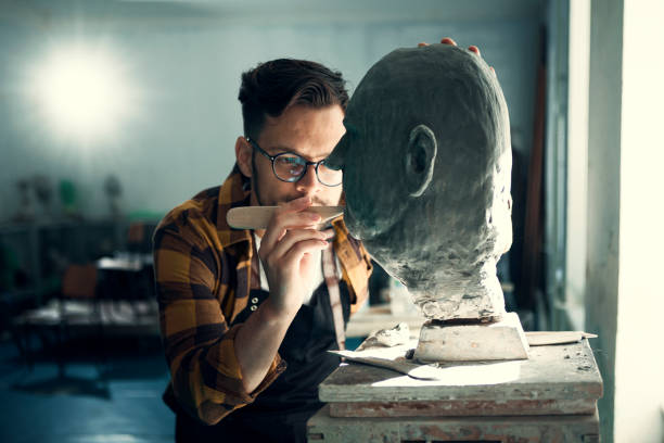 Contemplating work Young man sculpting head out of clay artist sculptor stock pictures, royalty-free photos & images