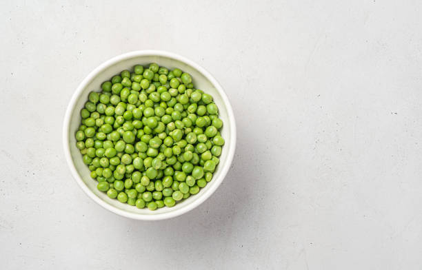 istock Fresh green peas in a white thicket on a gray background with space for copying 1328921248