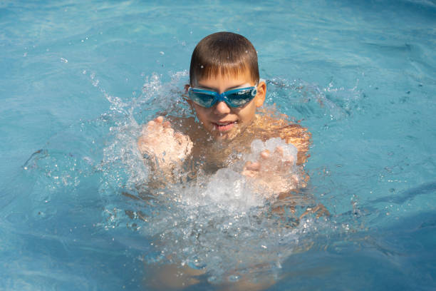 istock boy bathes in the pool wearing swimming goggles 1328922423