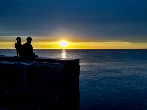 High contrast sunset silhouette scene male gay couple watching the view, montevideo, uruguay