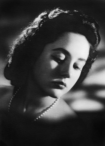 Vintage Studio headshot of a pensive young woman looking down