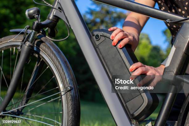 Detail Of Woman Holding An Electric Bike Battery Mounted On Frame Stock Photo - Download Image Now