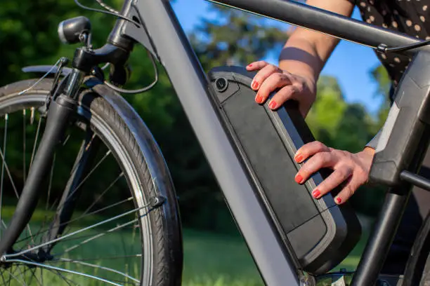 Photo of detail of woman holding an electric bike battery mounted on frame