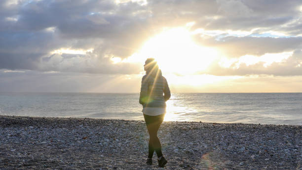 istock Woman walks down beach in the winter 1328929664