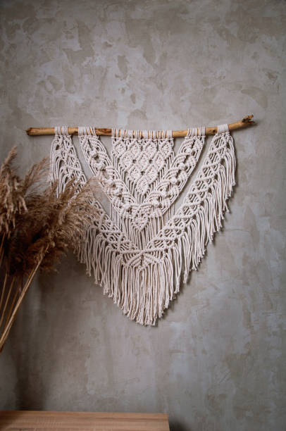 istock Handmade macrame 100 cotton wall decoration with wooden stick hanging on a white wall. 1328938404