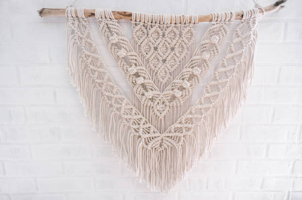 istock Handmade macrame 100 cotton wall decoration with wooden stick hanging on a white wall. 1328938486
