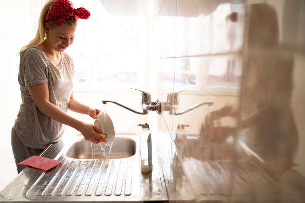 istock Happy house wife washing plate in bright modern kitchen 1328952875