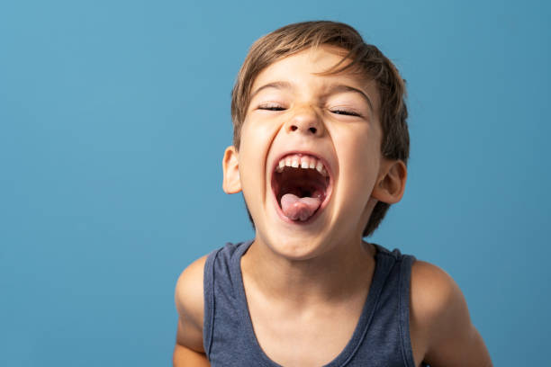 istock Front view of small caucasian boy four years old standing in front of blue background studio shot playful child making faces happiness and joy concept 1328957522