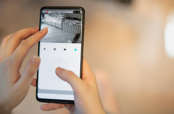 istock Female hand holding smartphone for watching home security camera for check safety their restaurant. 1328958160