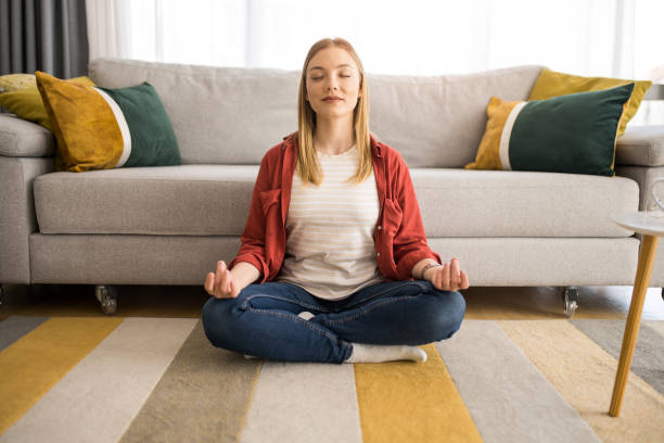 Meditation makes me grateful for life. Young mindful woman meditating in the living room. in the center stock pictures, royalty-free photos & images