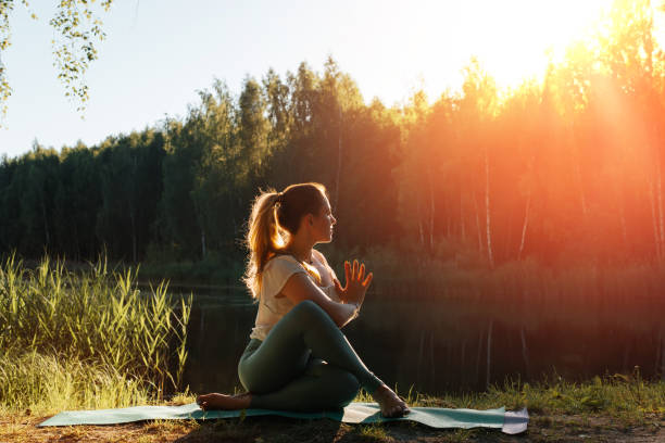 йога и медитация в природе. спортивная молодая женщина, медитируя на закате или восходе солнца, на открытом воздухе. девушка-йог, практикующ - pose of sage marichi стоковые фото и изображения