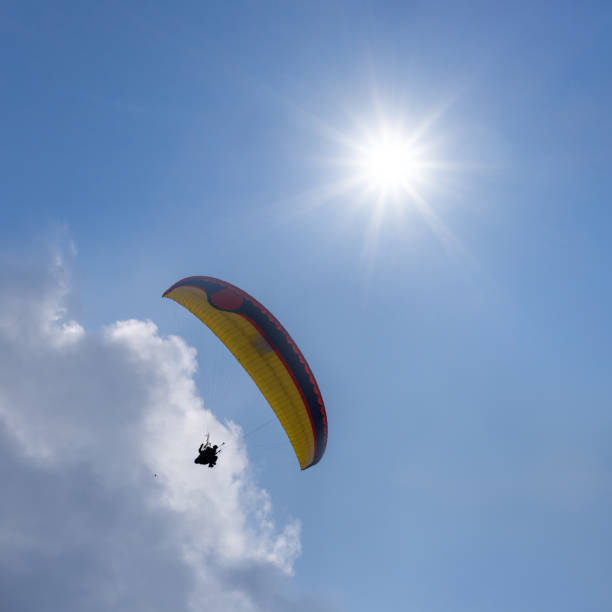 istock paraglider flying in suny cloudy sky, extremal sport background 1328973723