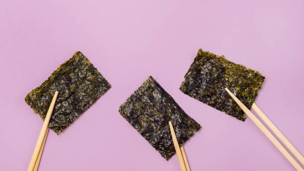 Small Crispy Nori Sheets Pink Background Healthy Japanese Snack Horizontal Banner Bamboo Chopsticks Small Crispy Nori Sheets Pink Background Healthy Japanese Snack Horizontal Banner Bamboo Chopsticks nori stock pictures, royalty-free photos & images
