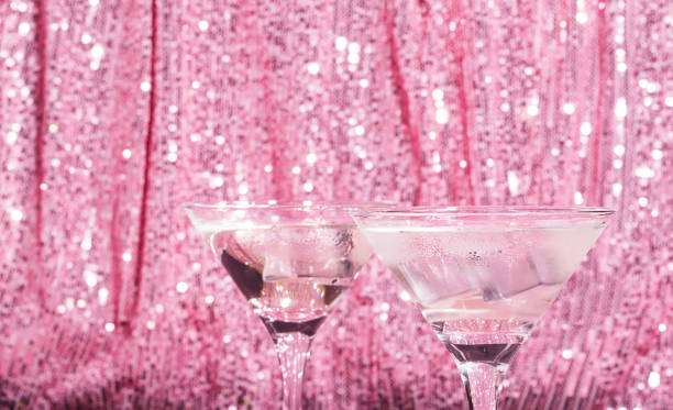 마티니 칵테일 배경 핑크 빛나는 커튼. 우아한 유리에 얼음을 곁들인 알코올 클래식 음료 - gin tonic water martini olive 뉴스 사진 이미지
