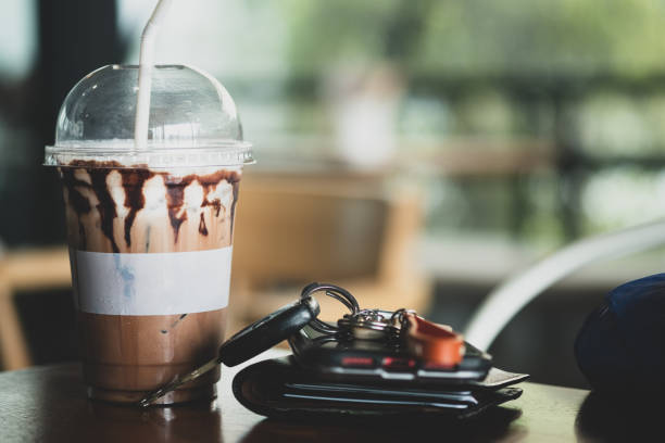 Iced coffee in a plastic glass with men wallet, mobile phone and car keys in the cafe Iced coffee in a plastic glass with men wallet, mobile phone and car keys in the cafe car keys table stock pictures, royalty-free photos & images