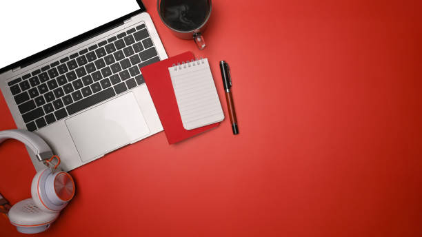 istock Mock up laptop, headphone, notebook and coffee cup on red background. 1328982107