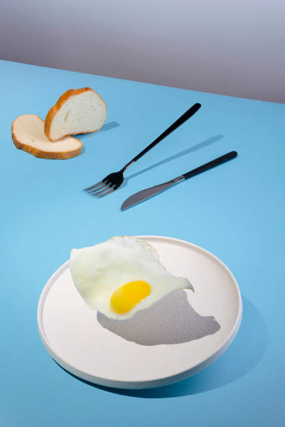 istock flying fried eggs plate on the modern blue background, vertical orientation 1328983322