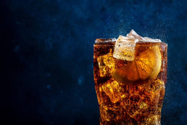 istock Cold cola with lemon and ice on blue background 1328983325