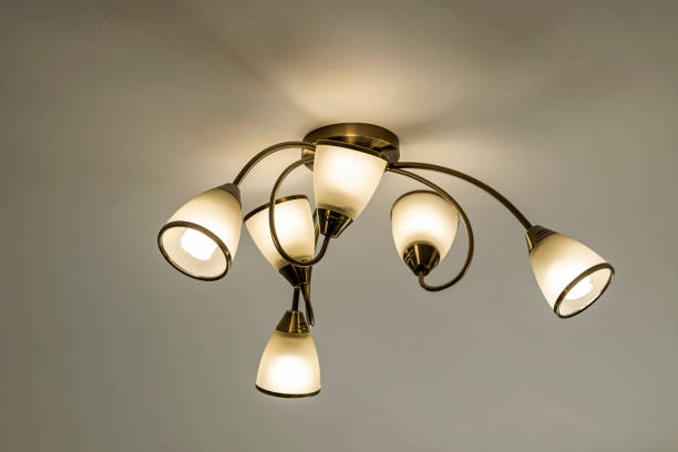 istock Modern electric lamp, chandelier with burning bulbs with soft light on a beige wall background 1328989323