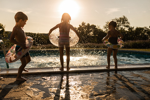 Carefree kids having fun during summer sunset at the pool in the backyard. Copy space.