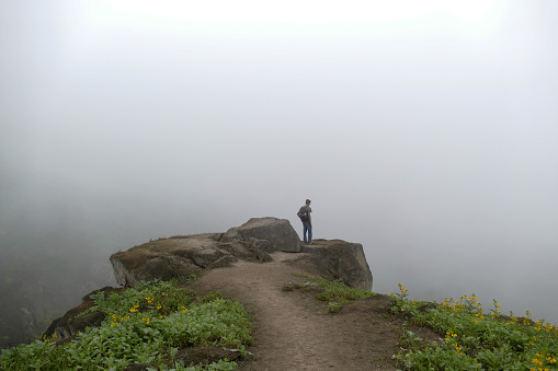 Smiling female backpacker inhaling the fresh air during foggy day on a mountain. Copy space.