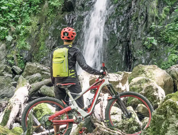 Photo of Cyclist at waterfall background