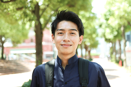 Young asian student looking at camera and smiling at university.