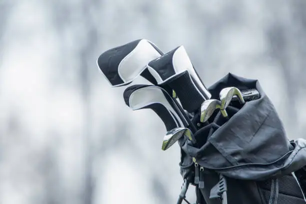 Photo of Golf clubs in a bag on a cart on a golf course.