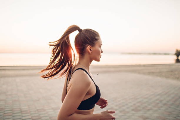 istock Young woman running by the river at sunrise 1328998838