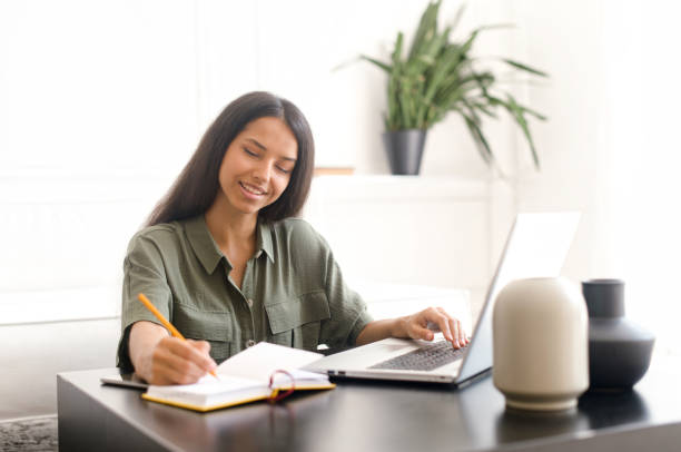 istock Smiling indian female student using laptop for watching webinars 1328999372