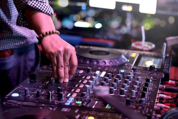 istock DJ hand playing live set and mixing music on controller turntable console mixing desk at stage in the night club, music beach party festival and nightlife concept. 1329000540
