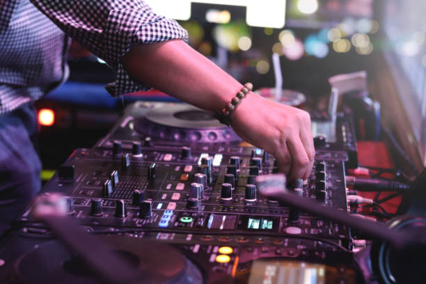 istock DJ hand playing live set and mixing music on controller turntable console mixing desk at stage in the night club, music beach party festival and nightlife concept. 1329000542