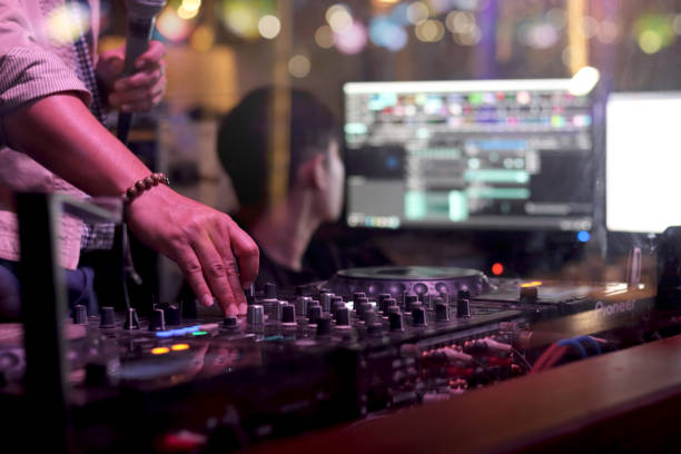 istock DJ hand playing live set and mixing music on controller turntable console mixing desk at stage in the night club, music beach party festival and nightlife concept. 1329000565
