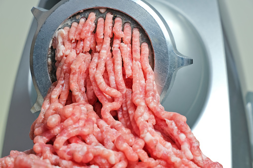 close up of freshly ground pork minced in an electric meat grinder