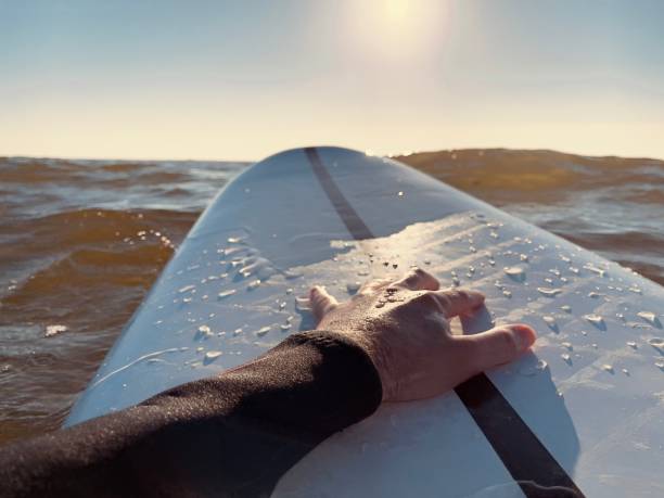 istock Water scene - surfer's hand on a white surfboard. Surfing in sunset. 1329004047