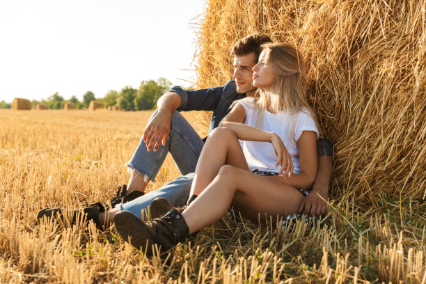 istock Smiling young couple sitting together at a haystack 1329004314